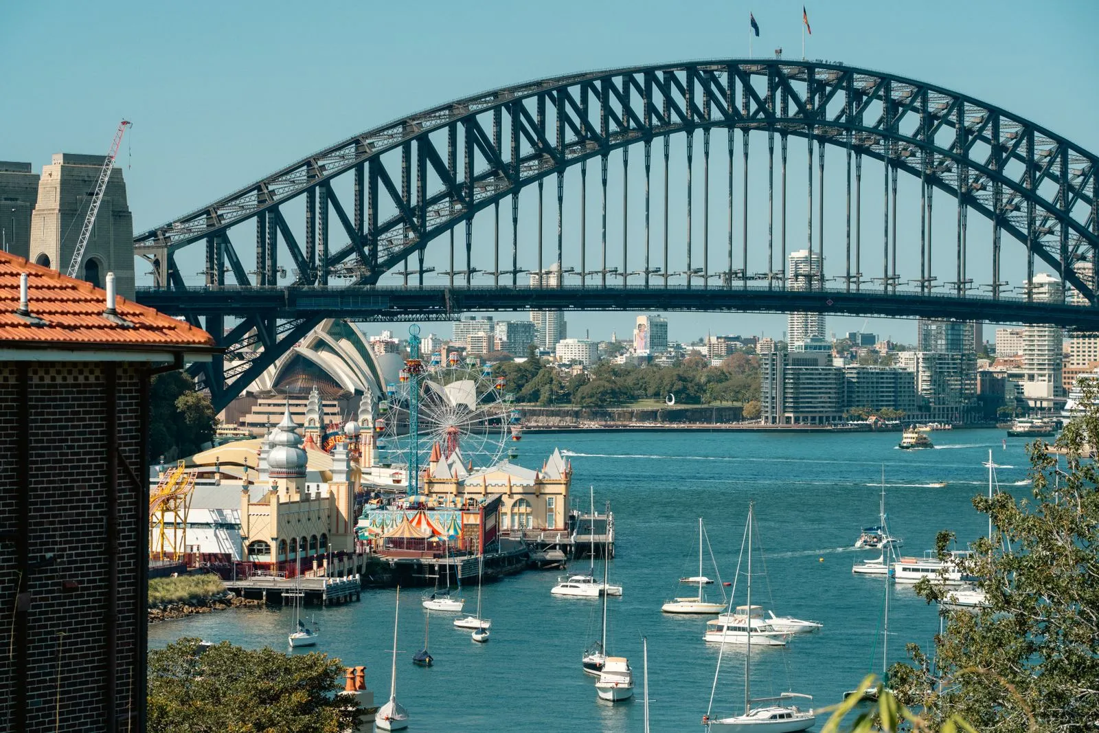 Sydney Harbour Bridge seen from the northern shore with Luna Park below — runners start on this side and finish across the water at the Opera House.
